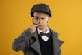 Cute little detective with magnifying glass on yellow background