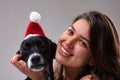 Cute little dog wearing a Santa hat with a smiling young woman Royalty Free Stock Photo
