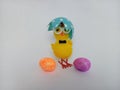 Cute little easter chick wearing an egg shell as a hat with two colorful Easter eggs on a white background Royalty Free Stock Photo