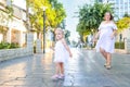 Cute little emotional blondy toddler girl in dress with pregnant mother playing, catching soap bubbles during walk in the city par Royalty Free Stock Photo