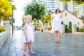 Cute little emotional blondy toddler girl in dress with pregnant mother playing, catching soap bubbles during walk in the city par Royalty Free Stock Photo