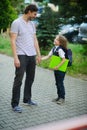 Cute little first grader is with his father in the school yard.