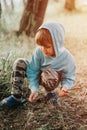 Cute little five year old kid boy in blue hoodie collects twigs of brushwood for campfire in the village on nature outdoor on a su Royalty Free Stock Photo