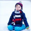 Cute little funny boy in colorful winter clothes having fun with Royalty Free Stock Photo