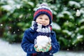 Cute little funny kid boy in colorful winter fashion clothes having fun and playing with snow, outdoors during snowfall Royalty Free Stock Photo