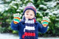 Cute little funny kid boy in colorful winter fashion clothes having fun and playing with snow, outdoors during snowfall Royalty Free Stock Photo