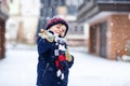 Cute little funny kid boy in colorful winter fashion clothes having fun and playing with snow, outdoors during snowfall Royalty Free Stock Photo