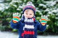 Cute little funny kid boy in colorful winter fashion clothes having fun and playing with snow, outdoors during snowfall Royalty Free Stock Photo