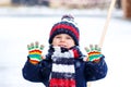 Cute little funny child in colorful winter fashion clothes having fun and playing with snow, outdoors during snowfall Royalty Free Stock Photo