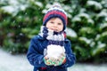 Cute little funny kid boy in colorful winter fashion clothes having fun and playing with snow, outdoors during snowfall Royalty Free Stock Photo