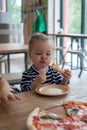 Cute little 2 years girl eating pizza in the restaurant