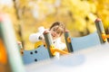 Cute little gilr playing on the playground at autumn