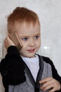 Cute little ginger baby boy with blue eyes speaks through mobile phone, smiling. Children and modern technology concept.