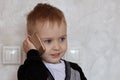 Cute little ginger baby boy with blue eyes speaks through mobile phone, smiling. Children and modern technology concept.