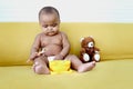 Cute little girl African American baby daughter trying to feed herself with spoon of food, infant kid enjoy eating healthy Royalty Free Stock Photo