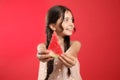 Cute little girl against red background, focus on hands with watermelon