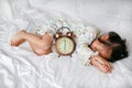 Cute little girl with alarm clock lying on bed Royalty Free Stock Photo