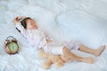 Cute little girl with alarm clock lying on bed Royalty Free Stock Photo