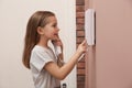 Cute little girl answering intercom call indoors Royalty Free Stock Photo