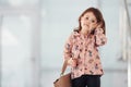 Cute little girl with bag indoors in the office or airport talking by phone Royalty Free Stock Photo