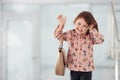 Cute little girl with bag indoors in the office or airport talking by phone Royalty Free Stock Photo