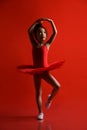 Cute little girl ballerina dancer in beautiful dress is dancing jumping on red background Royalty Free Stock Photo