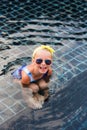 Cute little girl with a bandage on his head in the sun-colored glasses in the pool floating on a summer day.