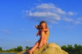 Cute little girl in a bathing suit sitting on a large rock by the lake. Summer and happy childhood concept. Copy space Royalty Free Stock Photo