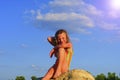 Cute little girl in a bathing suit sitting on a large rock by the lake at sunset. Summer and happy childhood concept Royalty Free Stock Photo