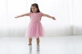 Cute little girl in beautiful dress is dancing at light sunny room.