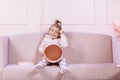 Cute little girl with a big pink gift box sitting on pink sofa, smiling and looking at the camera. happy childhood Royalty Free Stock Photo