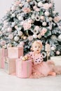 Cute little girl in bklom dress sitting in the flour and opens a box with a present for background Christmas tree . Xmas Royalty Free Stock Photo