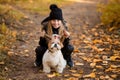 Cute little girl in a black coat with a dog walk in the park. A child is training a dog. Faithful friends of man. Leisure with