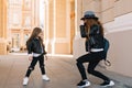 Cute little girl in black pants with holes on knees posing on the street, while her mother taking photo. Graceful young Royalty Free Stock Photo