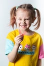 Cute little girl with blond hair is holding a pink dental myofunctional trainer Royalty Free Stock Photo