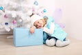 Cute little girl with blond hair posing beside a Christmas tree