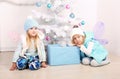 Cute little girl with blond hair posing beside a decorated Christmas tree