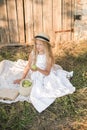 Cute little girl with blond long hair in a summer field at sunset with a white dress with a straw hat Royalty Free Stock Photo