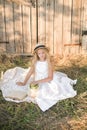 Cute little girl with blond long hair in a summer field at sunset with a white dress with a straw hat Royalty Free Stock Photo