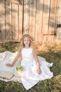 Cute little girl with blond long hair in a summer field at sunset with a white dress with a straw hat Royalty Free Stock Photo