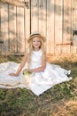 Cute little girl with blond long hair in a summer field at sunset with a white dress with a straw hat Royalty Free Stock Photo