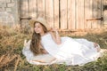 Cute little girl with blond long hair in a summer field at sunset with a white dress with a straw hat Royalty Free Stock Photo