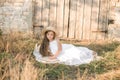 Cute little girl with blond long hair in a summer field at sunset with a white dress with a straw hat Royalty Free Stock Photo