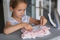 Cute little girl with blonde hair is leaning on ironing clothes on board at home. Daughter helping to mother ironing clothes for Royalty Free Stock Photo