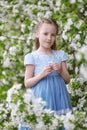 Cute little girl in blooming apple tree garden at spring