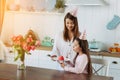 Cute little girl blowing out candles on birthday cake on kitchen with mother. Celebrating birthday at home. Royalty Free Stock Photo