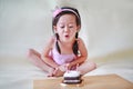 Cute little girl blowing small birthday candles, 2 years old kid celebrating