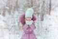 Cute little girl blows snow with mittens in winter snowy day