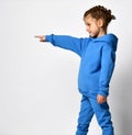 Cute little girl in blue hooded suit isolated on light background pointing with finger to the side and presenting Royalty Free Stock Photo