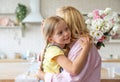 Cute little girl with bouquet hugging her grandmother in kitchen Royalty Free Stock Photo